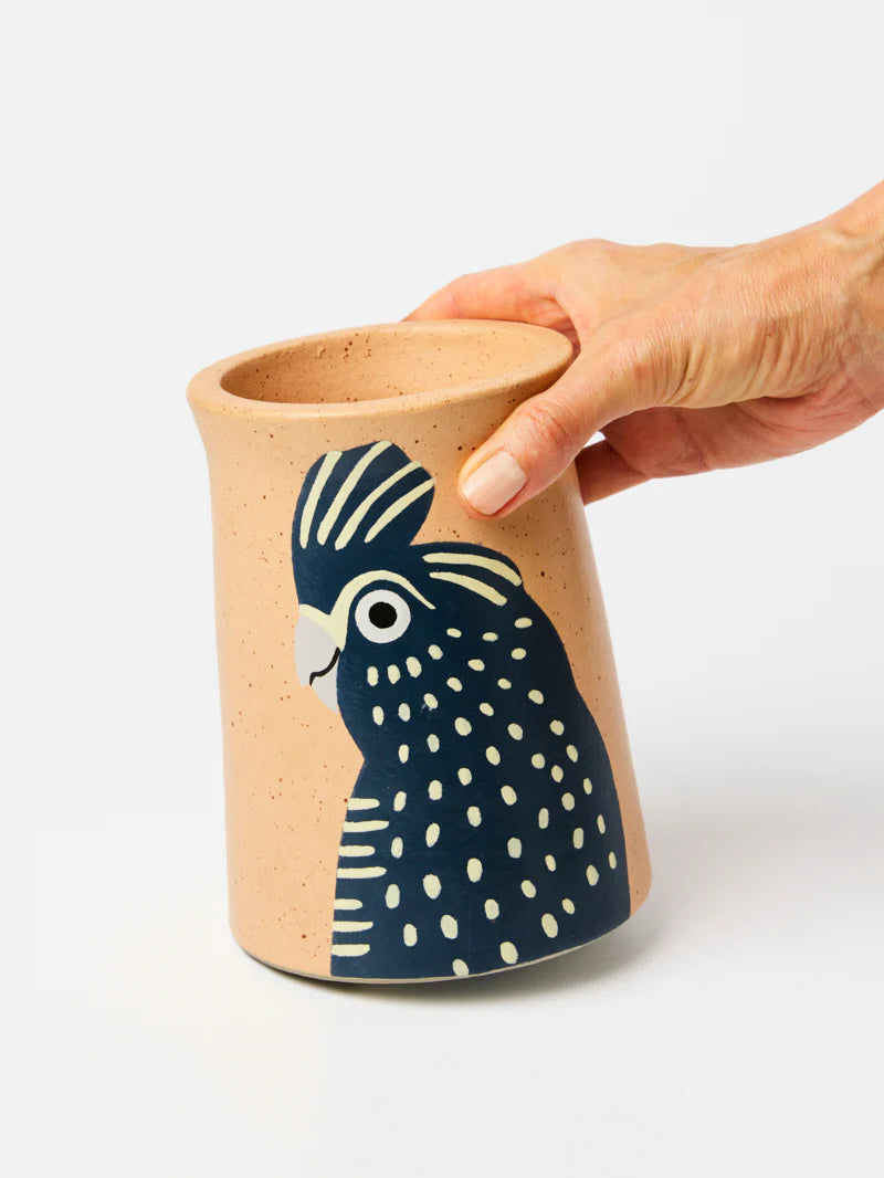 Ceramic mug with a bird design held by a hand on a white background