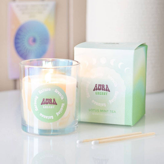 Candle with 'Aura' branding next to its packaging on a white surface