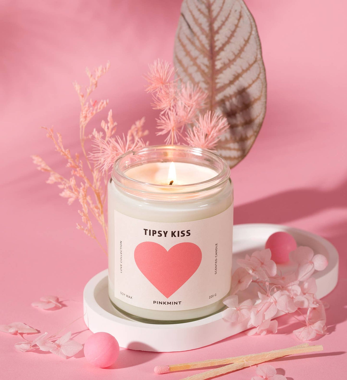 Candle labeled 'Tipsy Kiss' with a pink heart on a pink background