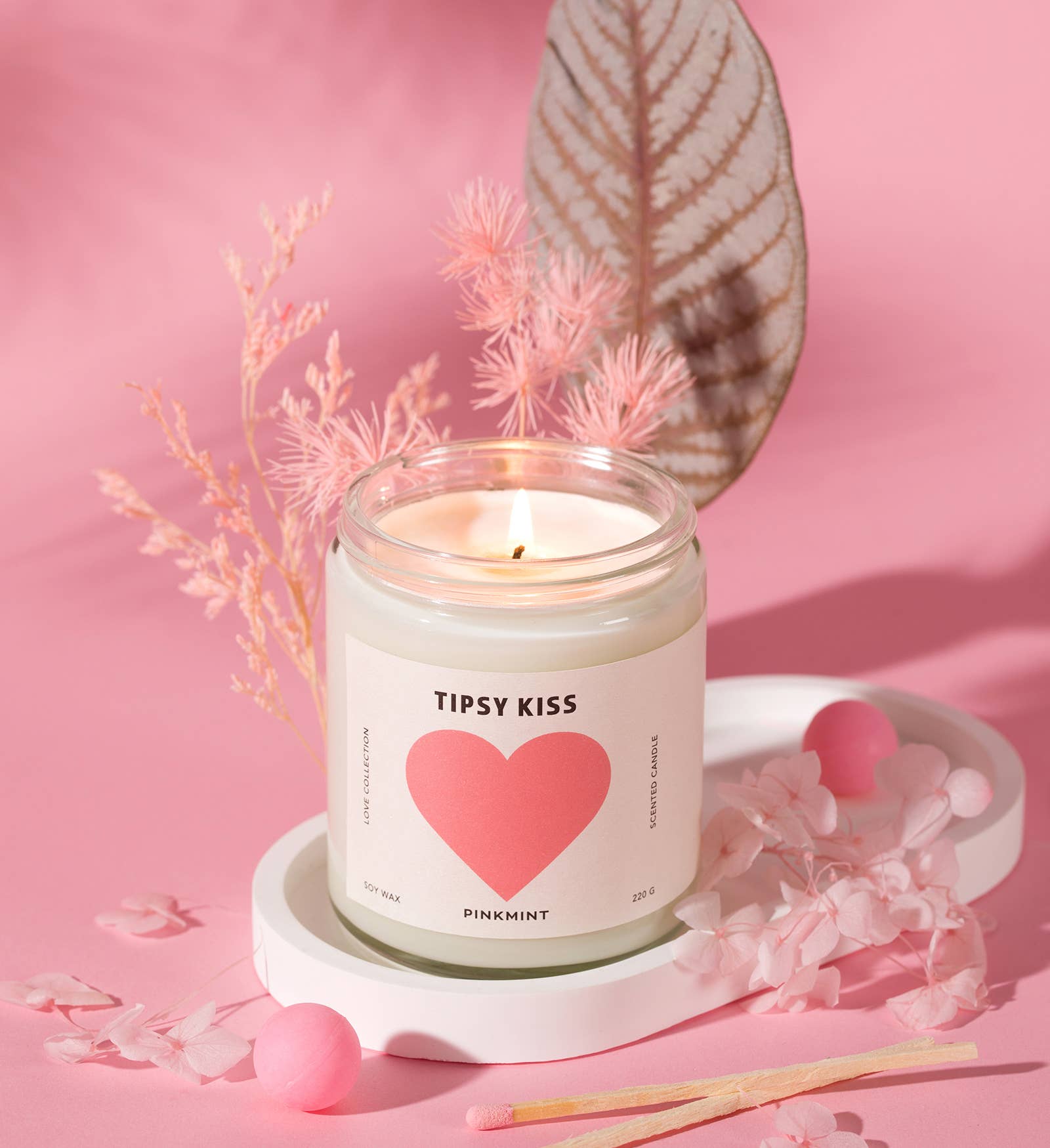 Candle labeled 'Tipsy Kiss' with a pink heart on a pink background