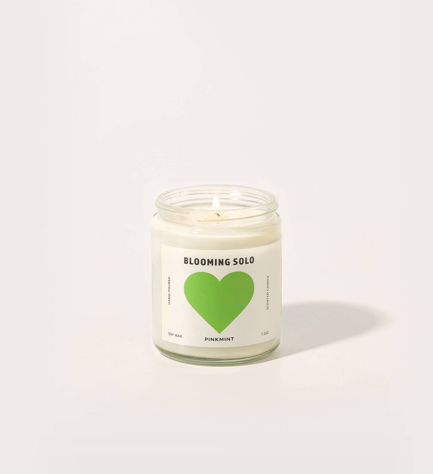 Candle with a green heart on a white label against a white background