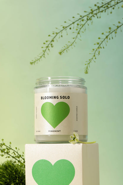 Candle in a jar with a green heart label on a light green background