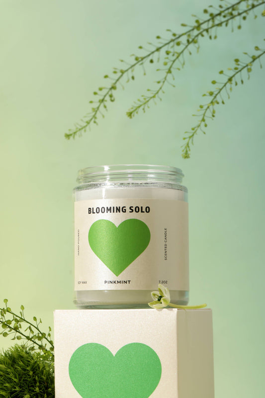 Candle in a jar with a green heart label on a light green background