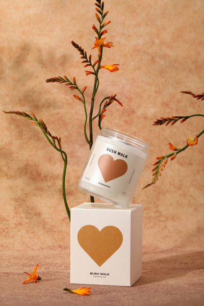 Candle and packaging with heart design on a beige background