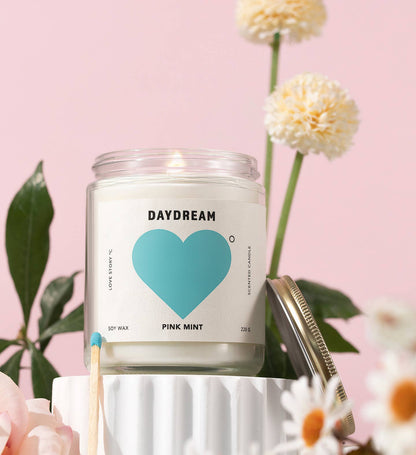 Candle jar labeled 'Daydream' with a blue heart on a pink background