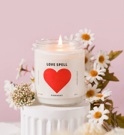 Candle labeled 'Love Spell' with a red heart on a pink background